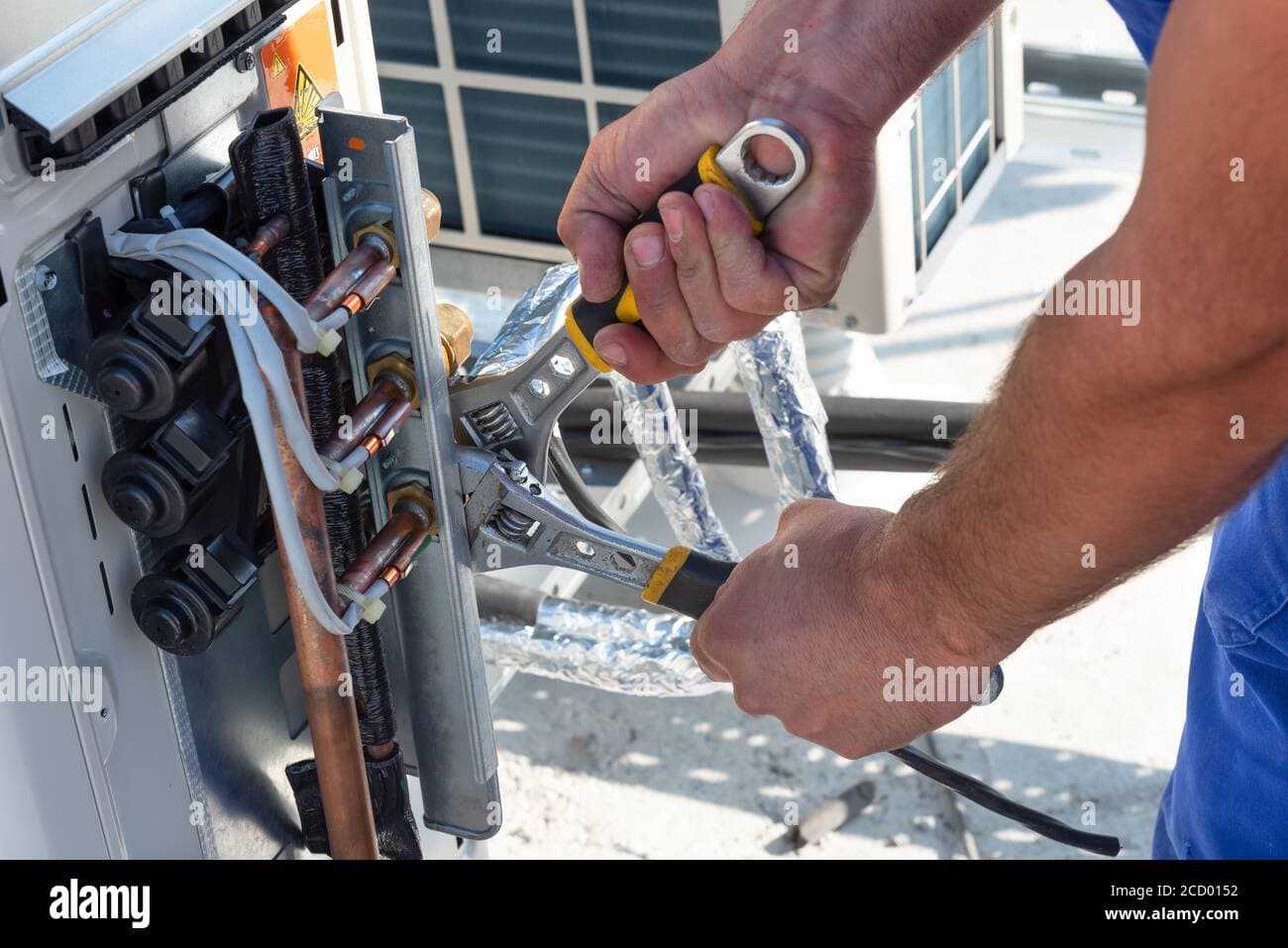 HVAC technician repairing a split AC indoor unit with manifold gauges