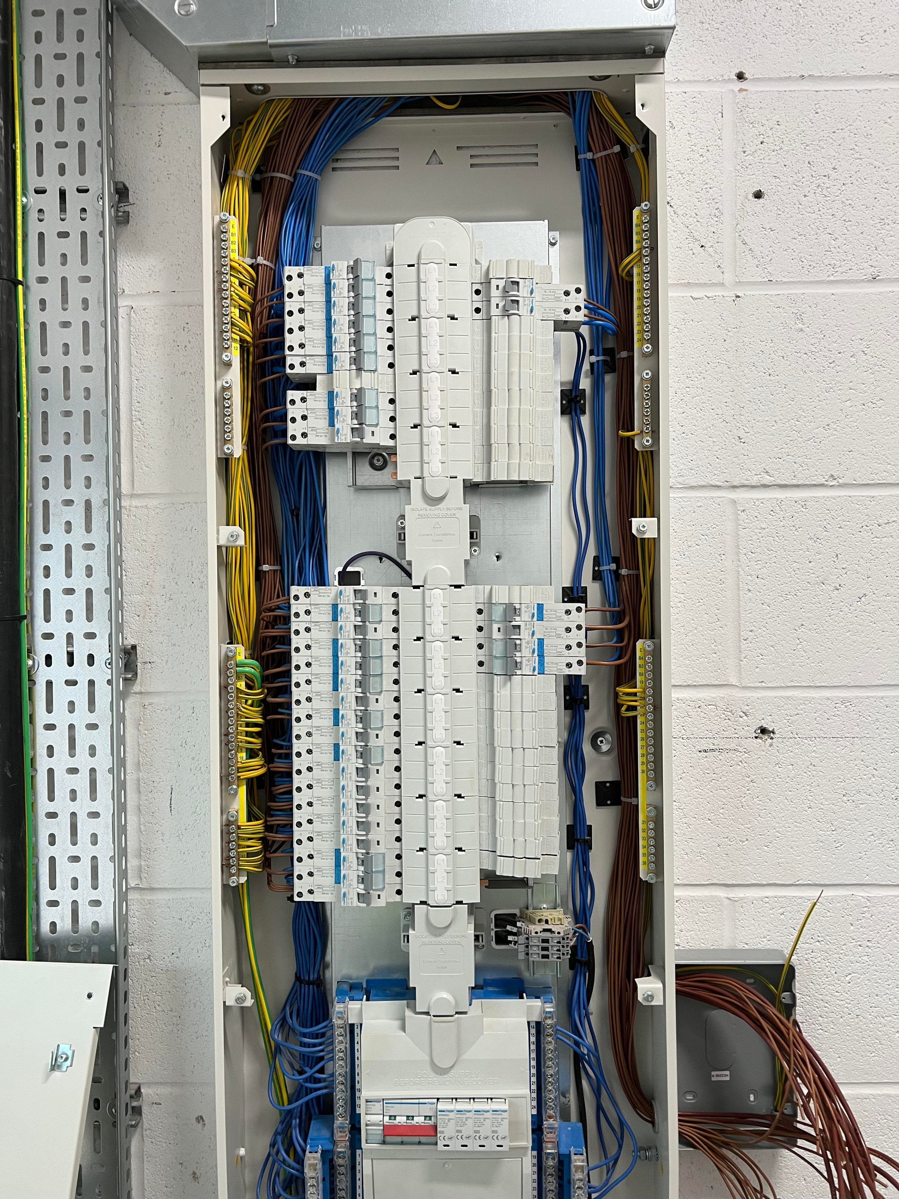 Licensed electrician working on a distribution board with multimeter