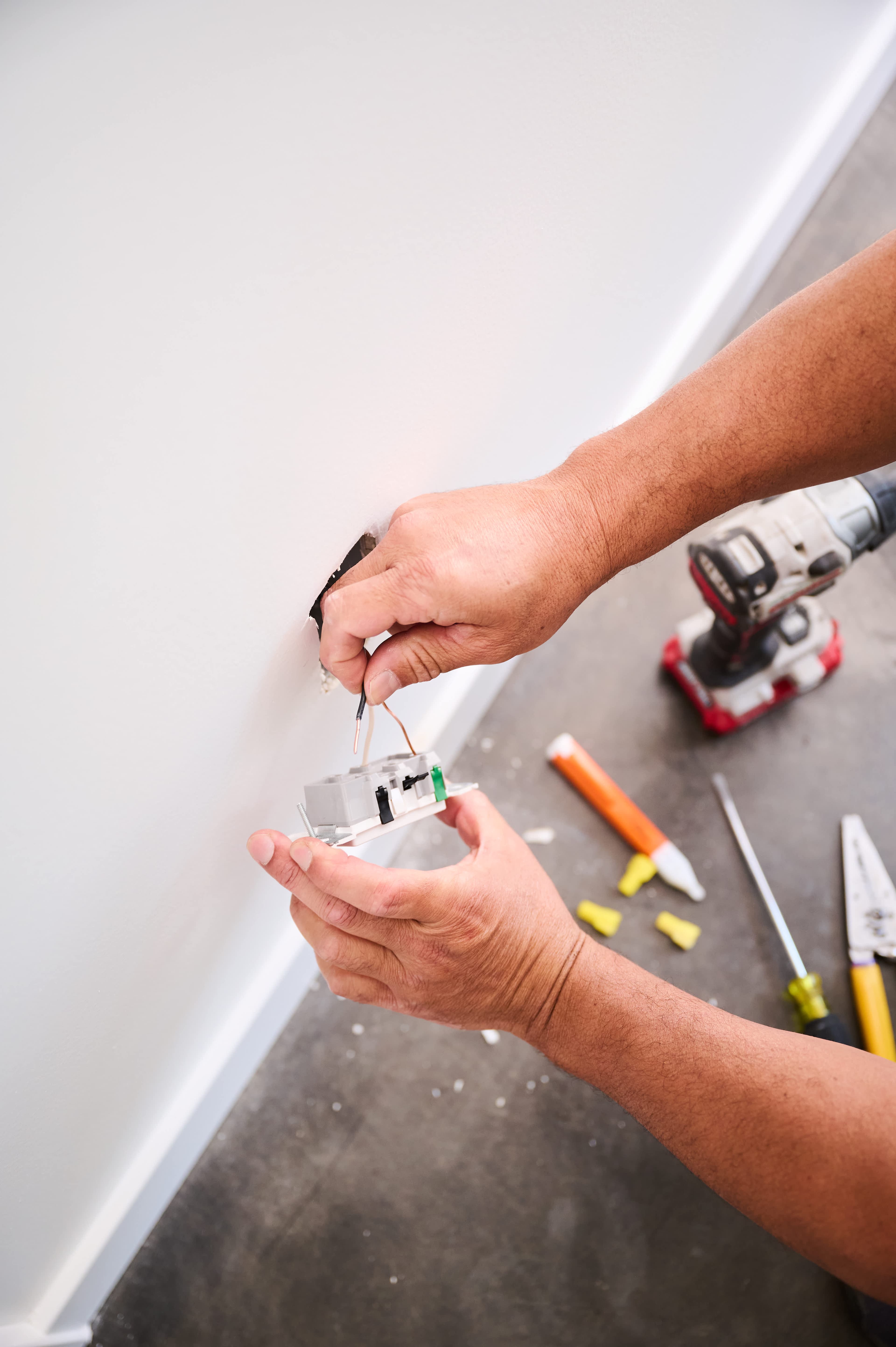 Licensed electrician installing a wall socket in uniform